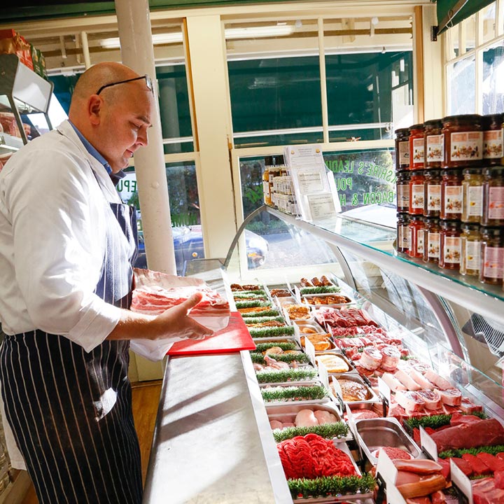 A butcher preparing meat at the Cowdery’s shop counter